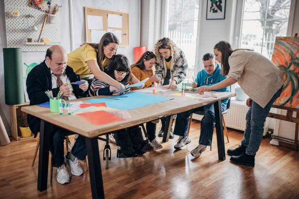 istock People with down syndrome and cerebral palsy doing an art project with help with assistants and animators.Disability health care art workshop. 1478379069