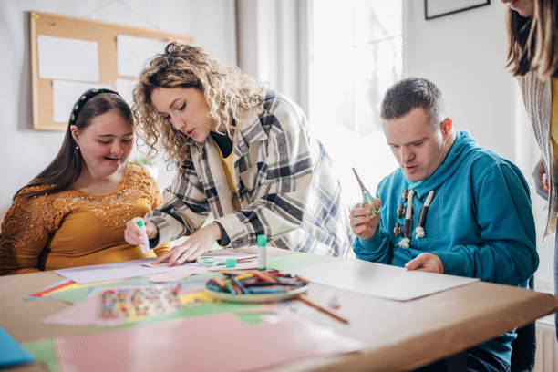 istock People with down syndrome and cerebral palsy doing an art project with help with assistants and animators.Disability health care art workshop. 1478379321