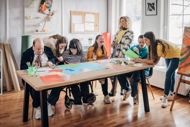 istock People with down syndrome and cerebral palsy doing an art project with help with assistants and animators.Disability health care art workshop. 1478380115