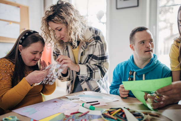 istock People with down syndrome and cerebral palsy doing an art project with help with assistants and animators.Disability health care art workshop. 1478380424