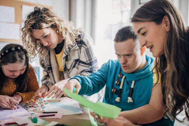 istock People with down syndrome and cerebral palsy doing an art project with help with assistants and animators.Disability health care art workshop. 1478380631