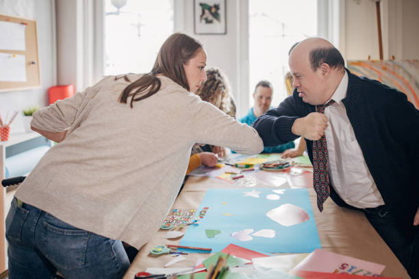 istock People with down syndrome and cerebral palsy doing an art project with help with assistants and animators.Disability health care art workshop. 1478381348