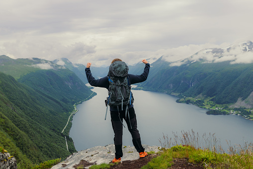 Rear View of Man with backpack contemplating beautiful summer landscape outdoors in Norway