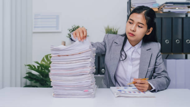 istock Young confident asian business woman office worker people working with stack of papers, unfinished documents of bookkeeping. 1478384996