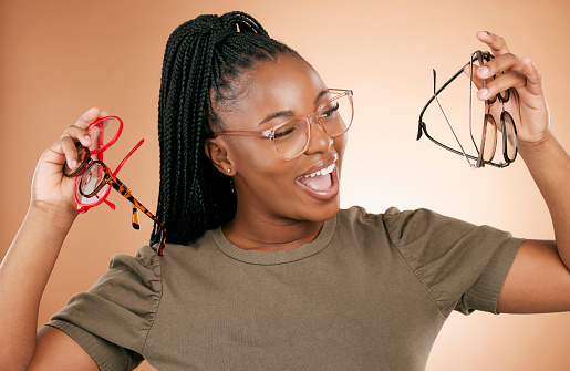 Excited, glasses frame choice and black woman with a smile from eye care and retail product. Studio background, isolated and beauty of a young student feeling happiness about glass frames shopping