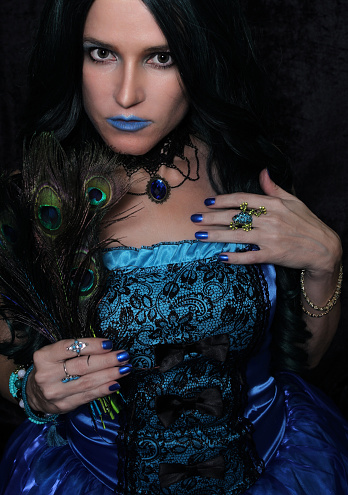 A vertical shot of a mysterious mystic female in a blue corset and accessories posing