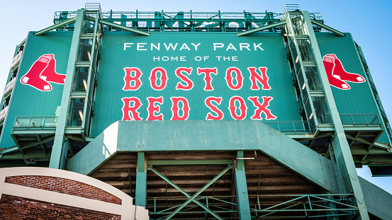 Boston, MA, USA - March 20, 2023: view of the historic architecture of the Fenway Park Stadium in Boston, Massachusetts, USA showcasing its sings and red brick walls on a sunny winter day.