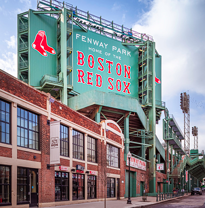 Boston, MA, USA - March 20, 2023: view of the historic architecture of the Fenway Park Stadium in Boston, Massachusetts, USA showcasing its sings and red brick walls on a sunny winter day.