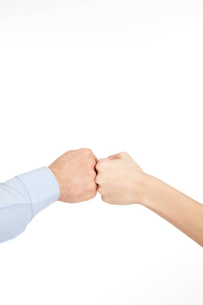 Two fists coming together in a symbolic gesture of solidarity and teamwork. The image captures the moment of a fist bump between individuals with different skin tones, emphasizing equality, unity, and mutual respect. Perfect for visual storytelling related to diversity, collaboration, teamwork, and friendship.