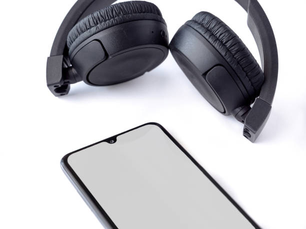 istock Black wireless headphone and mobile phone with a blank screen mockup on a white background 1478392666