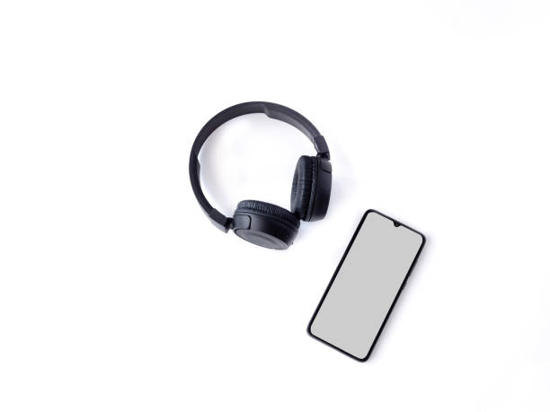 istock Black wireless headphone and mobile phone with a blank screen mockup on a white background 1478392671