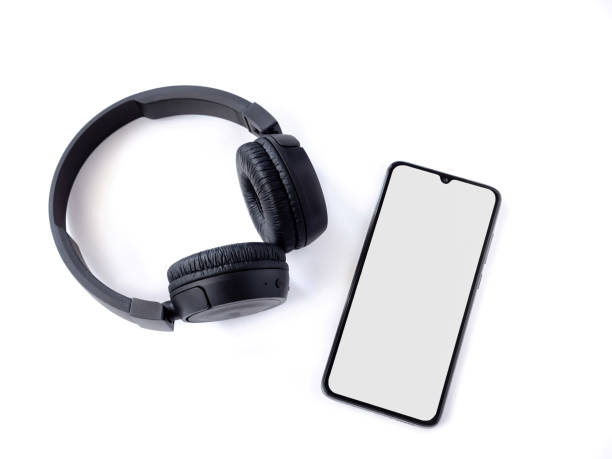 istock Black wireless headphone and mobile phone with a blank screen mockup on a white background 1478392674