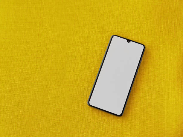 istock Flat lay of a smartphone with a blank white screen on a yellow surface - free space for text 1478392729