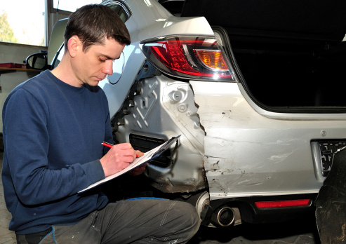Insurance expert inspecting car damage.