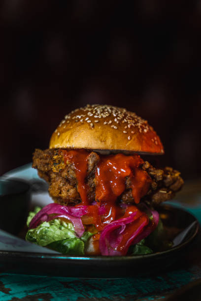 istock Vertical shot of a chicken burger in a dark grungy restaurant setting 1478397944