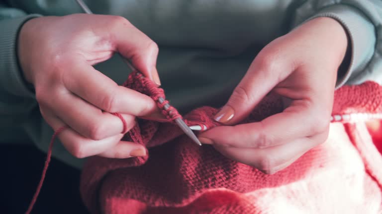 Close up on woman's hands knitting. Handmade woolen work.