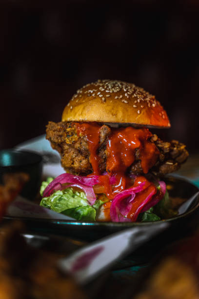 istock Vertical shot of a chicken burger in a dark grungy restaurant setting 1478398799