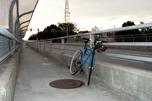 A blue mountain bike chained to a railing on a pedestrian walkway on a bridge