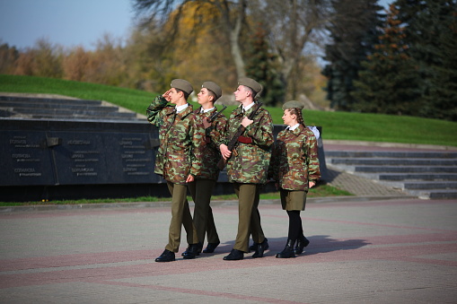 Young cadets in military uniforms are marching in the ranks to the memorial post. Belarus, Brest, October, 2022.