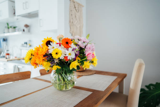 istock Kitchen counter table with focus on vase with huge multicolor various flower bouquet with blurred background of modern cozy white kitchen. Home interior design details. Mother's day. Copy space. 1478404023