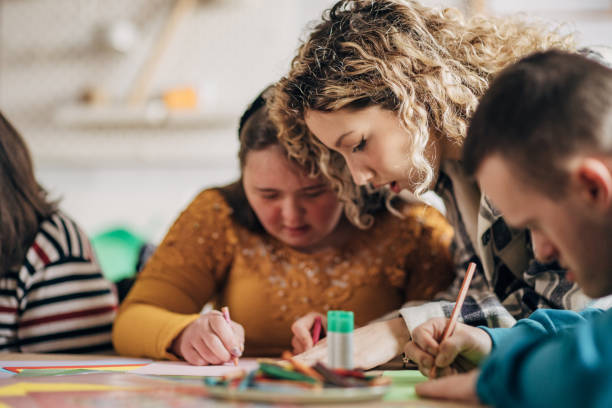 istock People with down syndrome and cerebral palsy doing an art project with help with assistants and animators.Disability health care art workshop. 1478406777