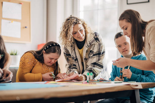 istock People with down syndrome and cerebral palsy doing an art project with help with assistants and animators.Disability health care art workshop. 1478407258