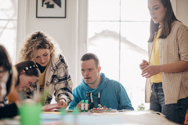 istock People with down syndrome and cerebral palsy doing an art project with help with assistants and animators.Disability health care art workshop. 1478407378