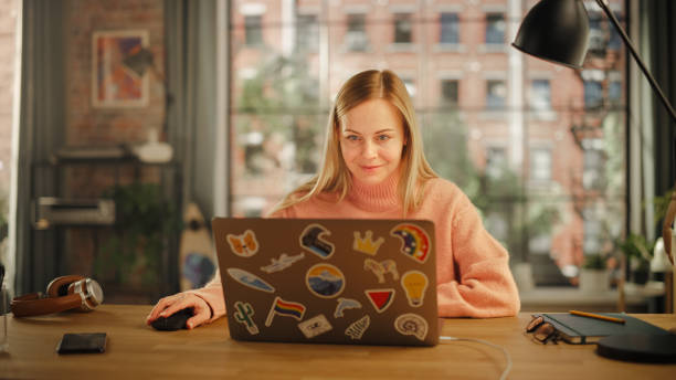 istock Beautiful Young Woman Working on Laptop Computer while Sitting in Stylish Cozy Creative Office. Freelancer Working Remotely from Home. Browsing Internet, Using Social Networks, Writing Project. 1478407484