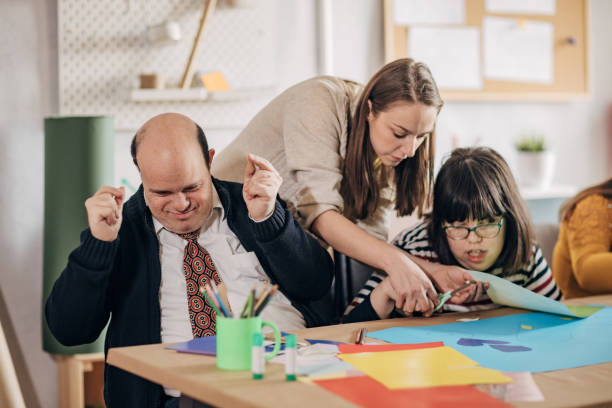 istock People with down syndrome and cerebral palsy doing an art project with help with assistants and animators.Disability health care art workshop. 1478408525