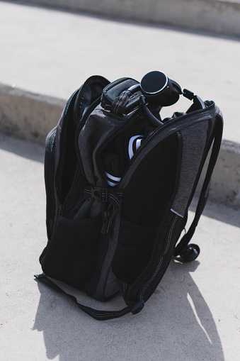 A vertical shot of a backpack with gym equipment outdoors