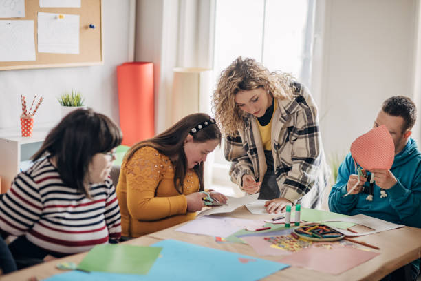istock People with down syndrome and cerebral palsy doing an art project with help with assistants and animators.Disability health care art workshop. 1478408927