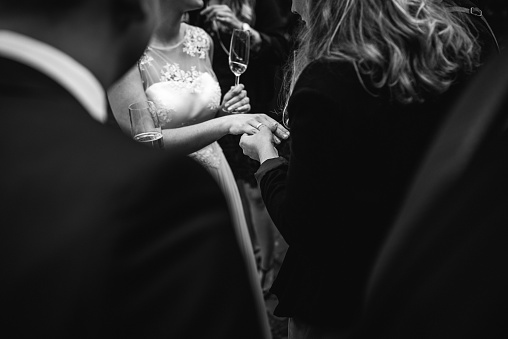 A close-up of a female wedding guest admiring the glimmering diamond engagement ring of the bride