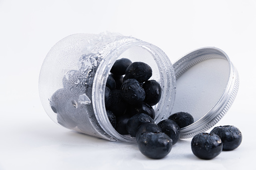 A closeup of fresh cold blueberries in a jar isolated on a white background