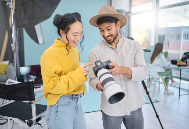 istock Camera, creativity and photographer talking to a model while looking at pictures from a photoshoot. Photography, creative and young cameraman choosing a image with a woman in creative artistic studio 1478410027