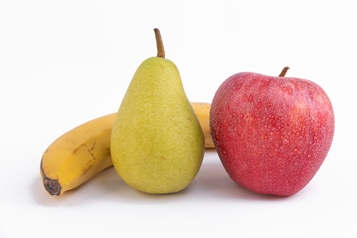A closeup of a fresh red apple with a banana and pear isolated on a white background