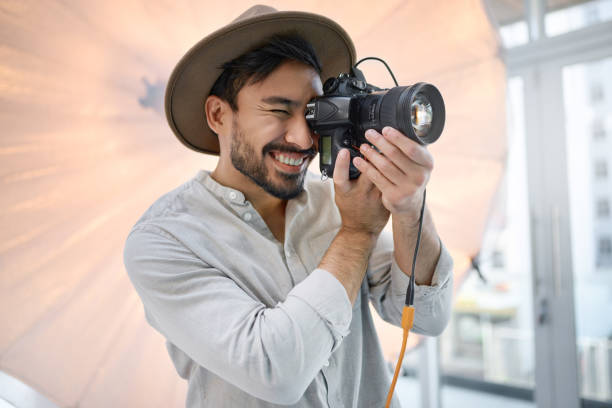 Photography, studio and camera with a man photographer taking a picture backstage during a photoshoot. Creative, light and production with a male using a photographic lens to take a photograph