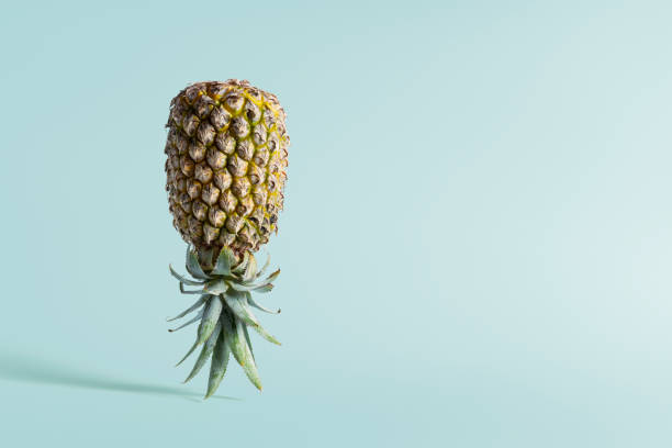 istock Inverted pineapple stands on a green background with a copy of the space. 1478410355