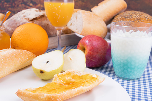 A closeup of ripe fruits with fresh bread loaves and drinks on the table