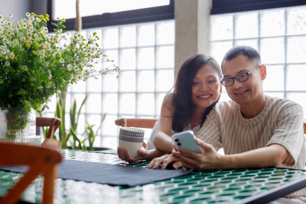 istock A happy young Asian couple is having coffee and chatting while using their smartphones together at home, enjoying a relaxing moment and spending quality time with each other. 1478414150