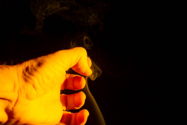 istock A male hand lit yellow with smoke around it 1478416751
