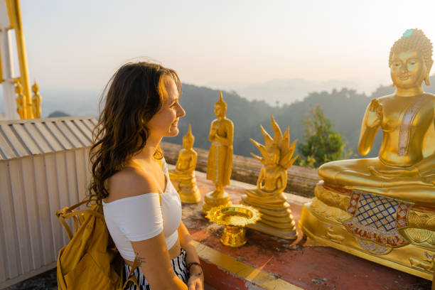 Woman looking at statue of golden buddha in temple Young Caucasian woman  looking at statue of golden buddha in temple wat tham sua stock pictures, royalty-free photos & images