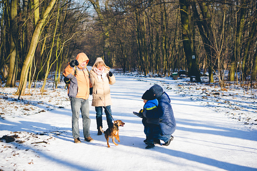 Poznan, Poland – January 28, 2017: Unidentified woman and man showing young boy a dog puppy on a frozen footpath at a park on a cold winter day