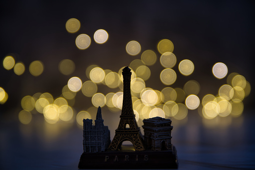 A miniature copy of the Notre Dame de Paris, the Eiffel Tower, and the Arch of Triumph in the bokeh effect lights background, a trip to Paris