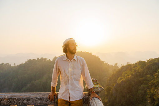 Young Caucasian man  standing on the top of wat Tham Sua in Krabi at sunset