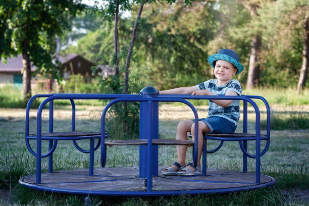 A happy child riding a merry-go-round on a beautiful and sunny summer day. stock photo