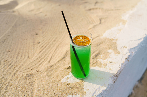 Green cocktail image taken in summer time on the sand.