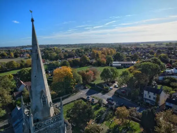 An aerial shot of a gothic church in the center of a rural town surrounded by trees and houses