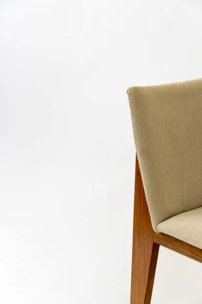 A detail of a modern chair with a white fabric seat and wooden legs isolated on a white background