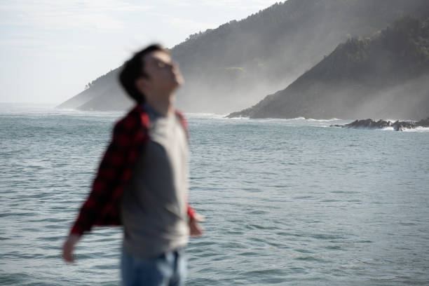 Unfocused person breathing deep in beautiful landscape. Teenager boy at coastline.