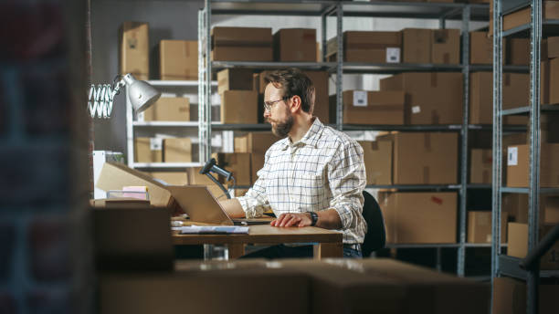 istock Male Inventory Manager Using Laptop Computer in Storeroom, Communicating with Clients, Writing Down Projects. Stylish Small Business Owner Working in Warehouse, Fulfilling Orders for Customers. 1478424649